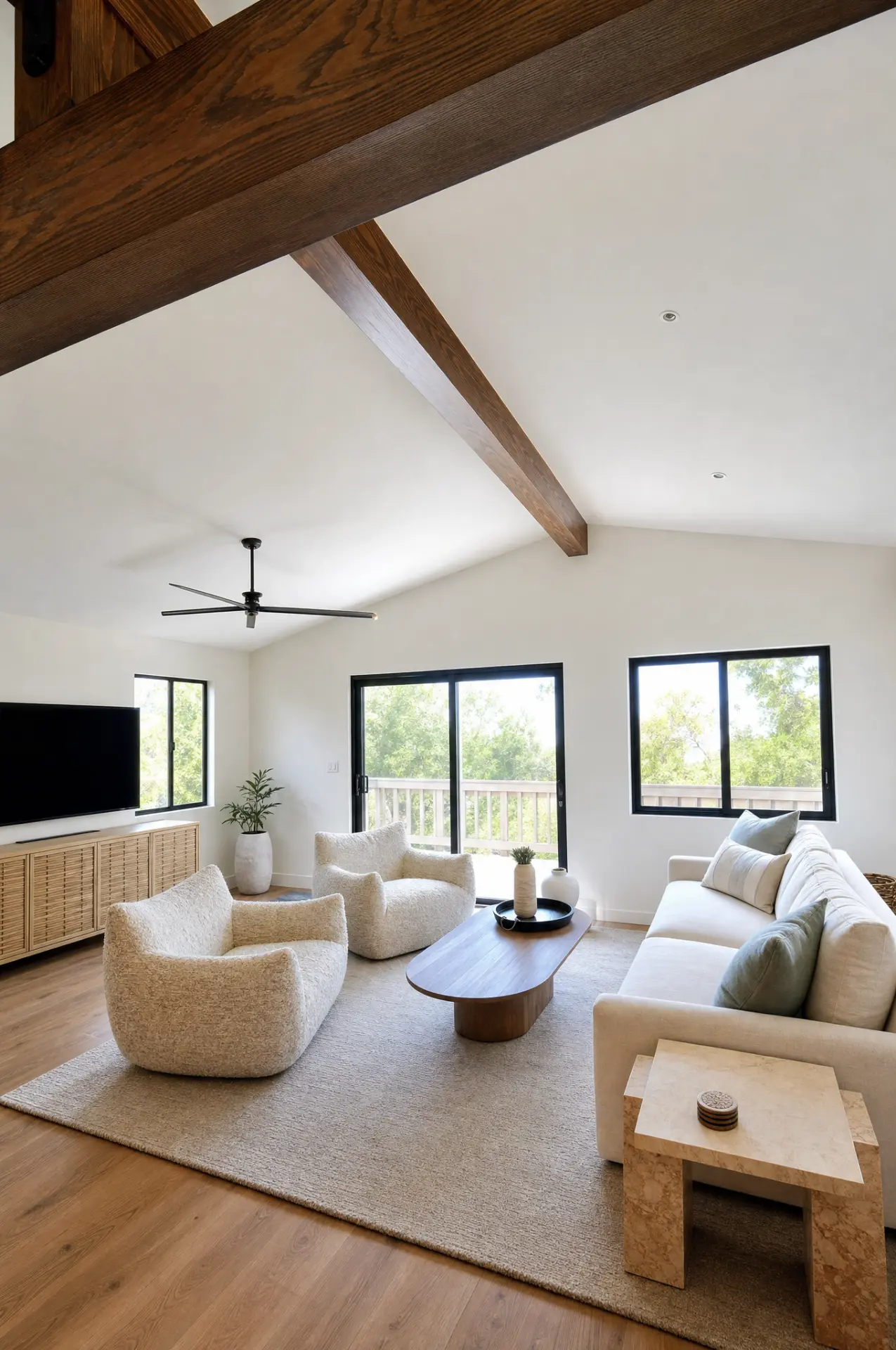 Bright living room with exposed timber beams, white sectional sofa and sliding glass doors