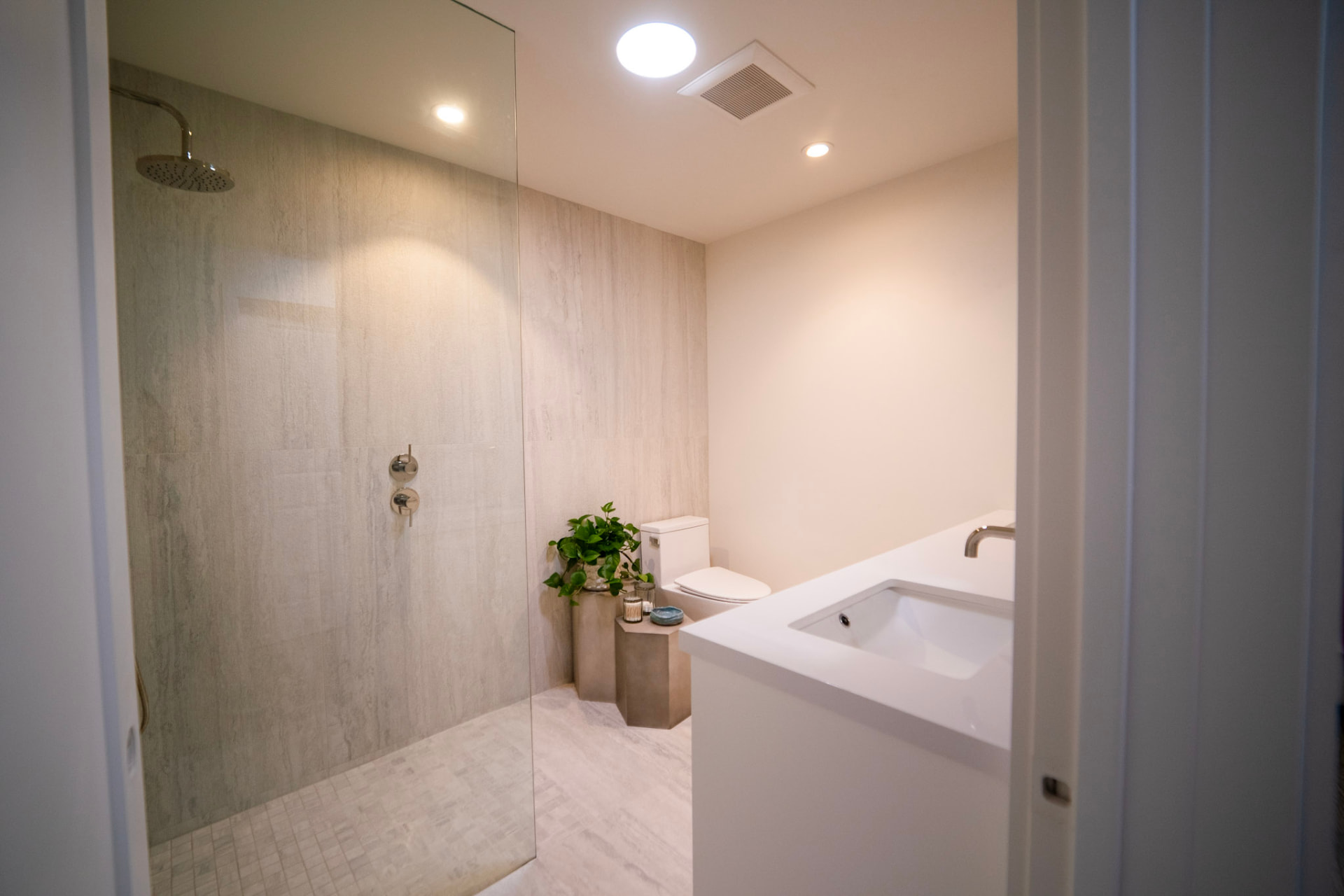 Spa-style bathroom with frameless glass shower, marble-look tile, floating vanity and brushed nickel fixtures