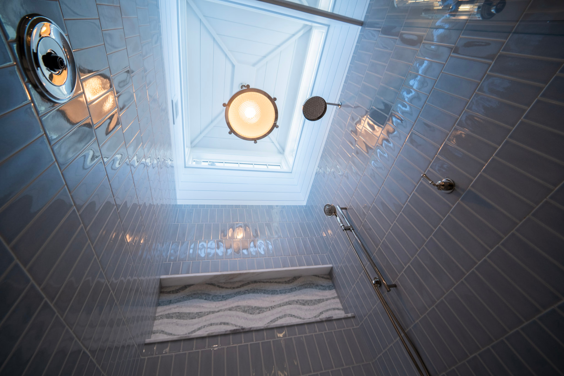 Walk-in shower with glossy blue subway tile, skylight and vintage-style ceiling light