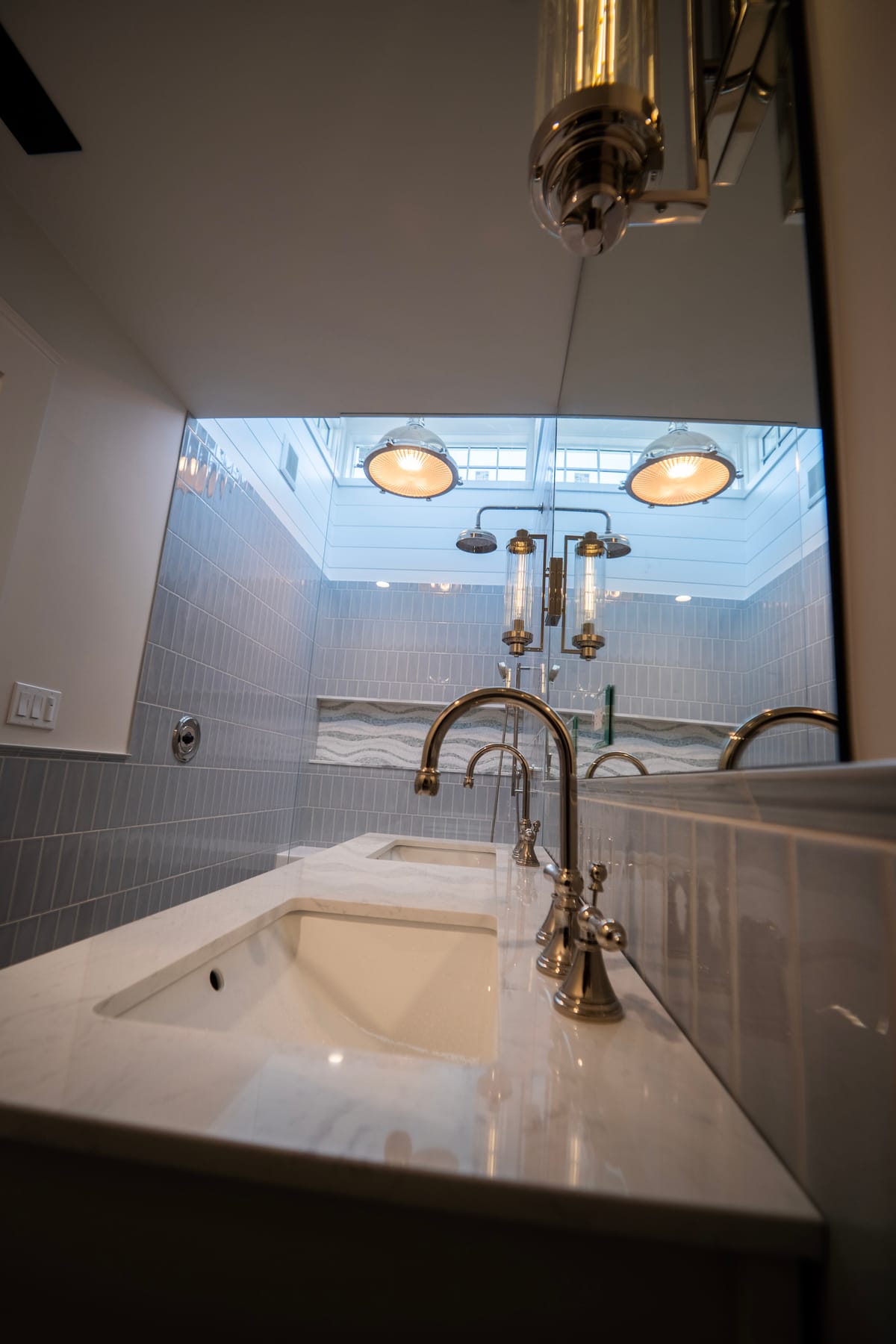 Vanity sink and faucet with a skylight and tiled shower beyond