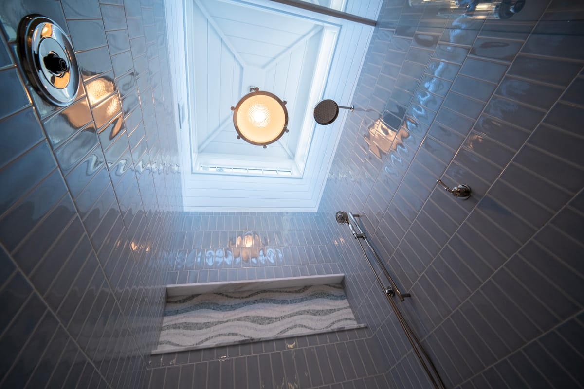 Walk-in shower with blue subway tile and a pendant skylight