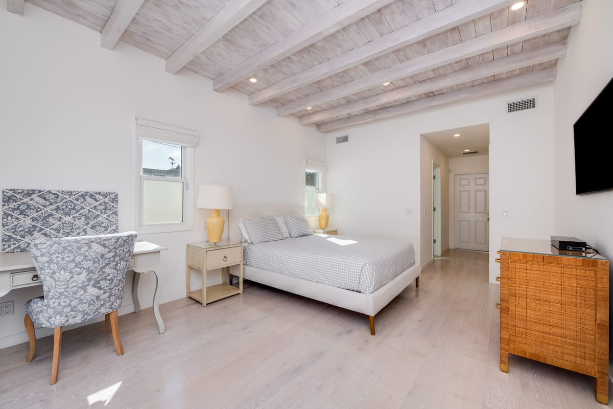 Renovated bedroom with a whitewashed exposed-beam ceiling