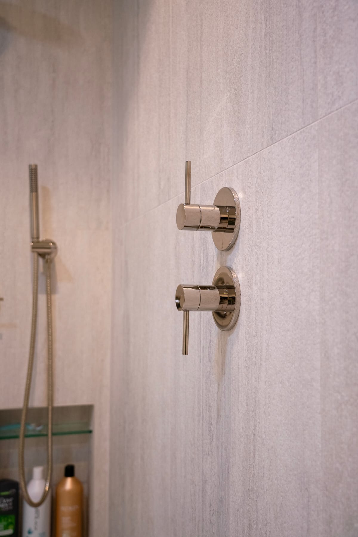 Polished shower fixtures against stone tile